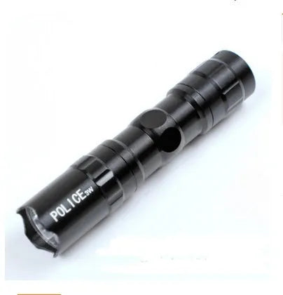 Black aluminium mini LED flashlight on a dark background, shown with AA battery for scale.