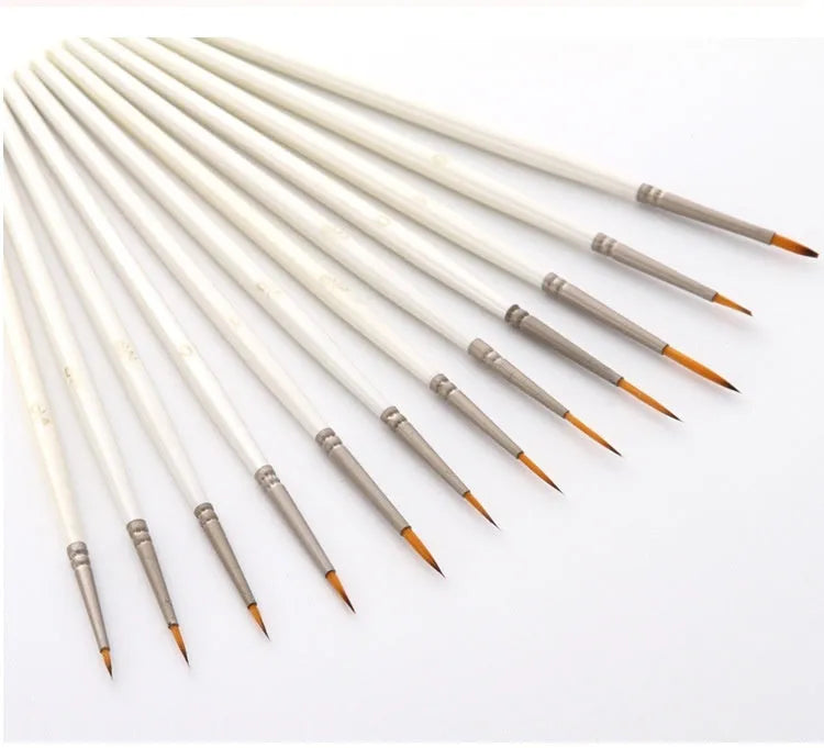 12 pearl white handled artist brushes with nylon wool bristles, stored upright in a solid wood pen holder.
