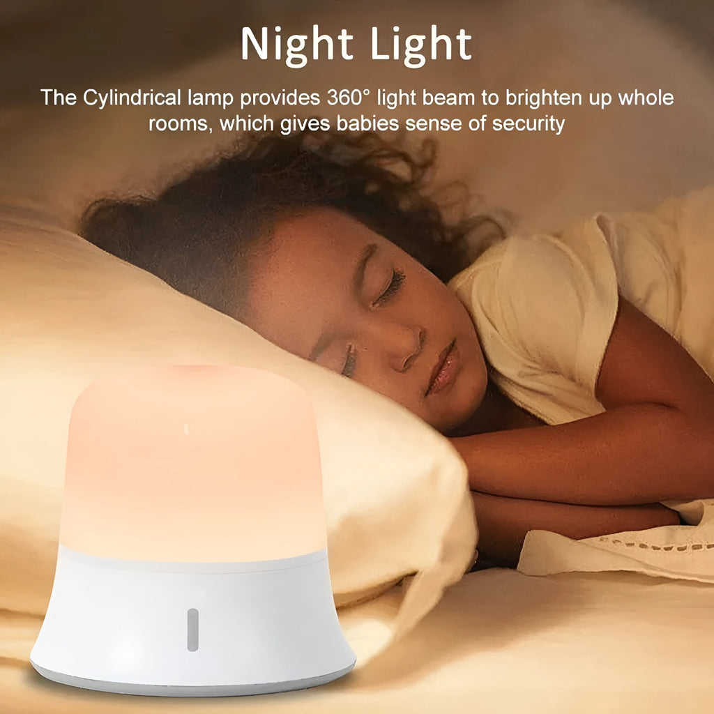 White cylindrical touch-control bedside night light with rechargeable battery on a table.