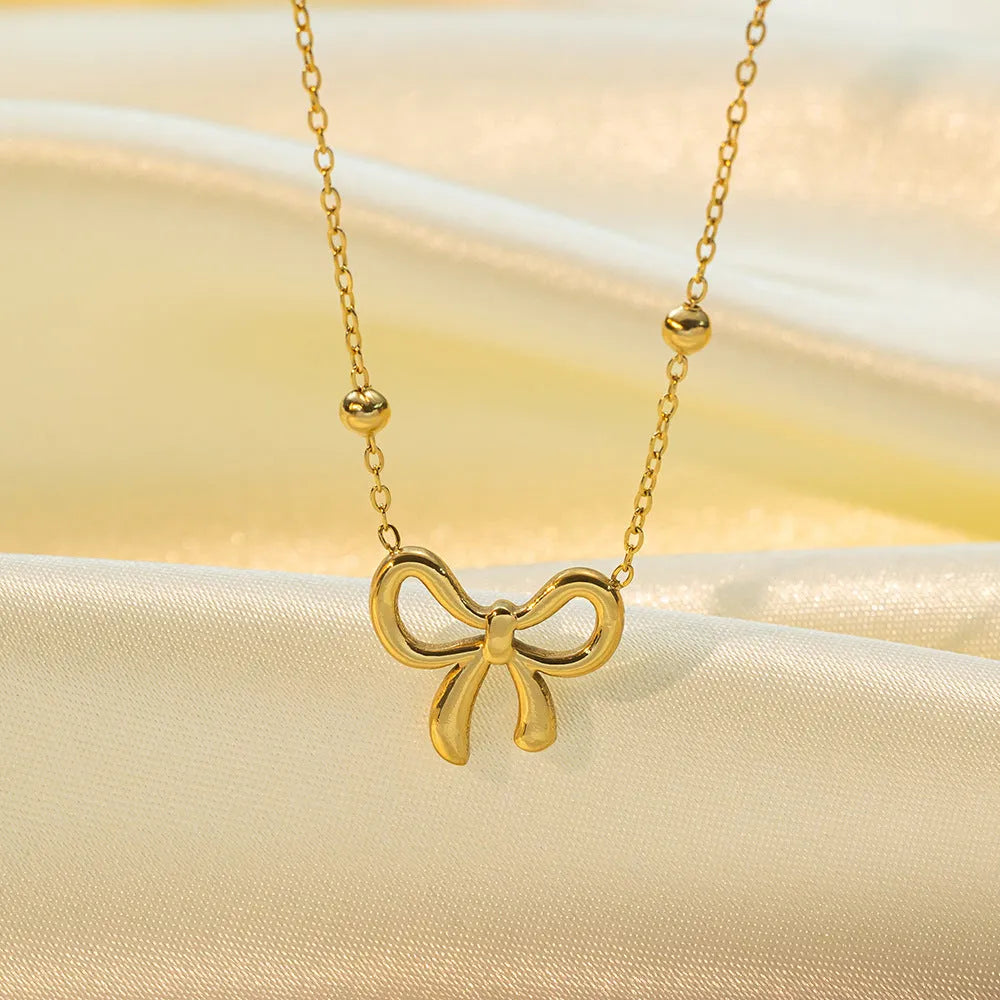 Gold electroplated bow pendant necklace with titanium steel cross chain, adjustable length