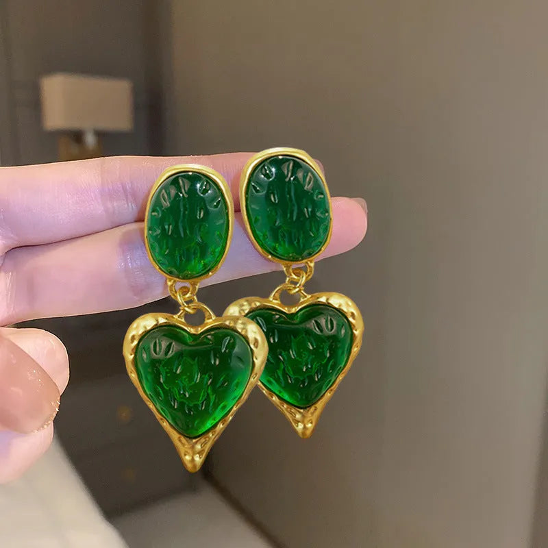 A pair of oval-shaped heart stud earrings with a silver needle texture in purple, red, green, and yellow white colours