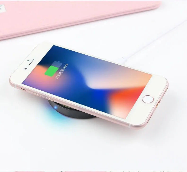 Qi wireless charging pad for mobile phones in six colour options on a wooden surface