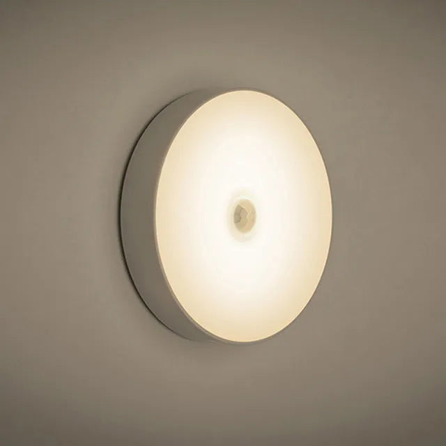Small round motion sensing night light with USB charging port and adhesive backing