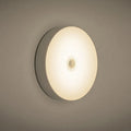 Small round motion sensing night light with USB charging port and adhesive backing