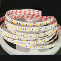 Close-up of a flexible white LED light strip with dense SMD LEDs, shown coiled, for shelf and counter lighting.