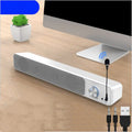 Compact black wired desktop computer speaker with USB and audio cables on a wooden desk.