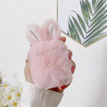 Pink silicone AirPods case cover with raised rabbit ears on a grey background.