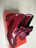 Black patent leather high heels with a thick block heel and square toe on a white background.