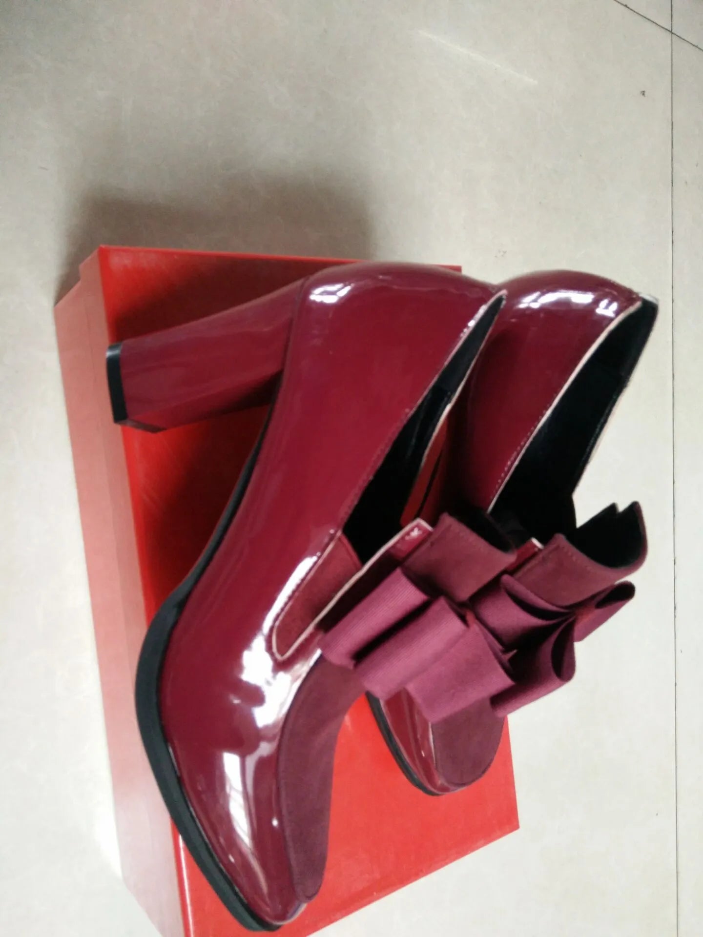 Black patent leather high heels with a thick block heel and square toe on a white background.
