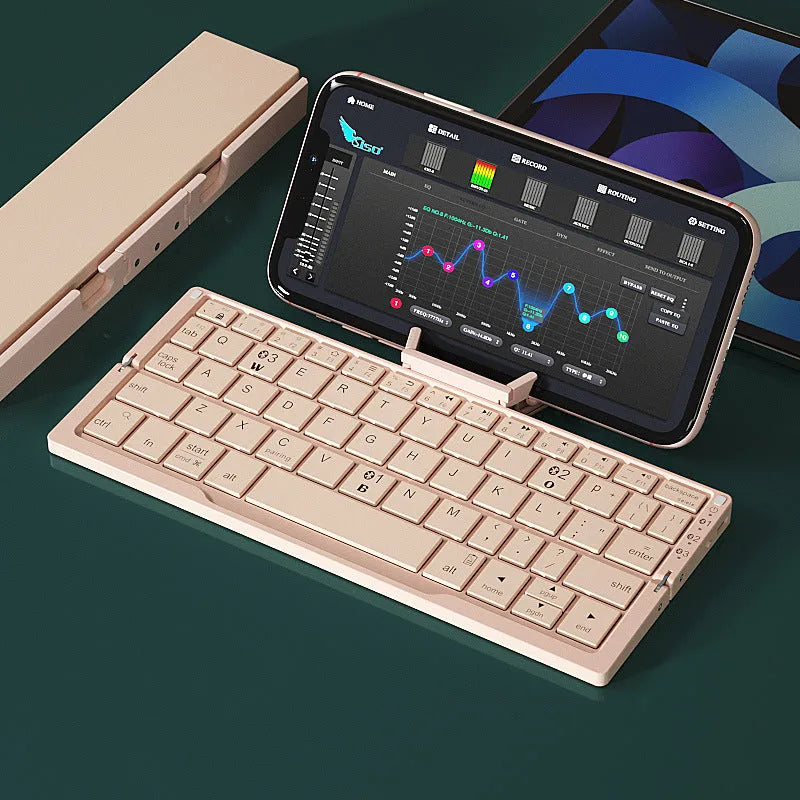 Aluminium folding Bluetooth keyboard with stand supporting smartphone, showing compact folded size