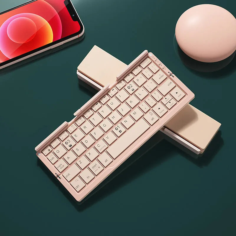 Aluminium folding Bluetooth keyboard with stand supporting smartphone, showing compact folded size