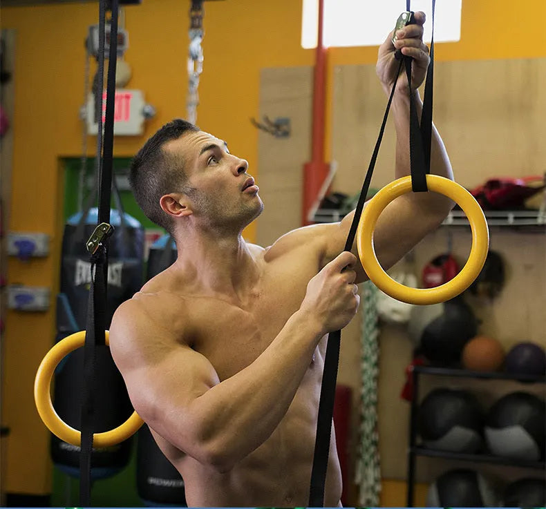 Black rubber encapsulated gymnastics training rings with ropes and gloves on indoor floor