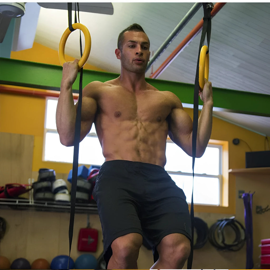Black rubber encapsulated gymnastics training rings with ropes and gloves on indoor floor