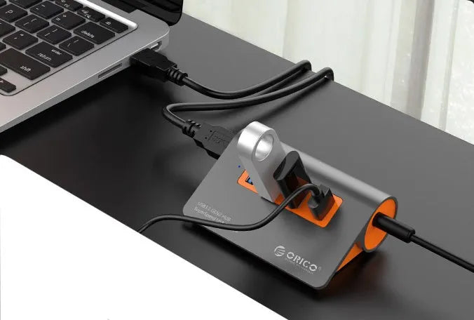 Dark grey and orange aluminium laptop USB hub with four USB 3.1 ports and a detachable cable.