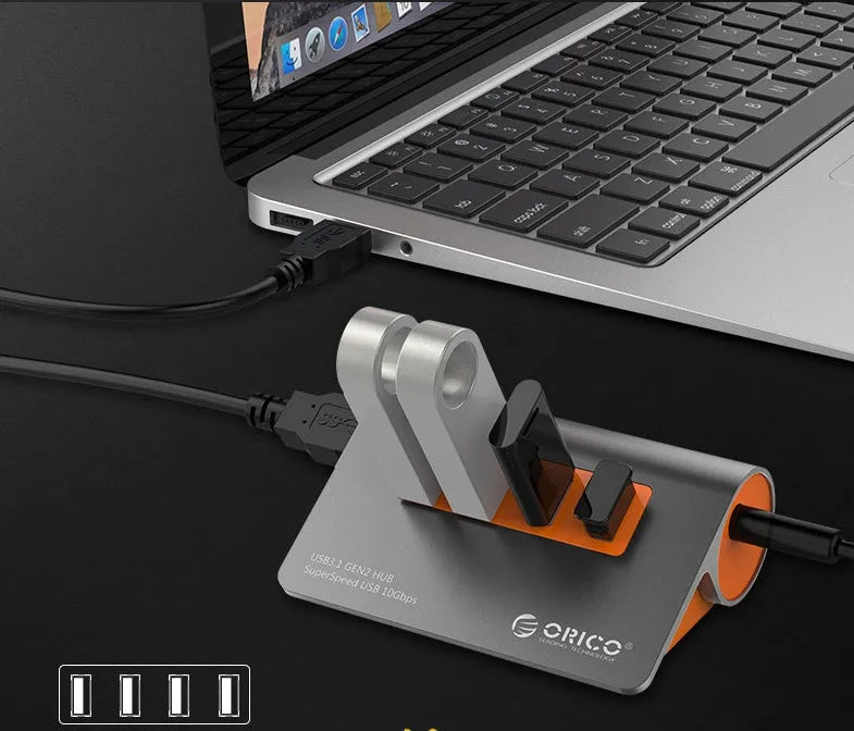 Dark grey and orange aluminium laptop USB hub with four USB 3.1 ports and a detachable cable.