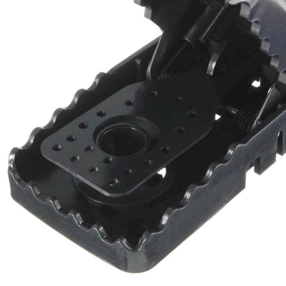 Set of six black plastic snapping mousetraps with smooth surfaces, shown next to a ruler for scale.