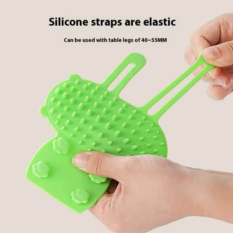 Silicone cat grooming brush with comb teeth mounted on table leg for scratching and hair removal