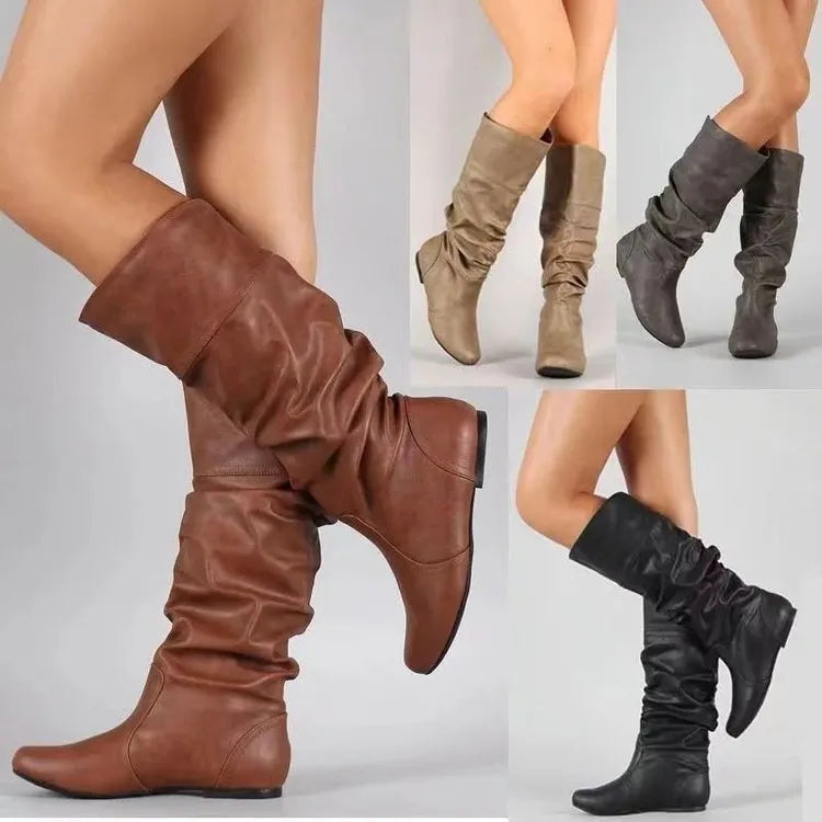 Women's black slip-on flat ankle boots with round toe and high cylinder shaft on a neutral background.