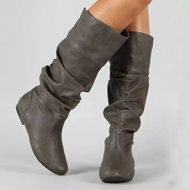 Women's black slip-on flat ankle boots with round toe and high cylinder shaft on a neutral background.