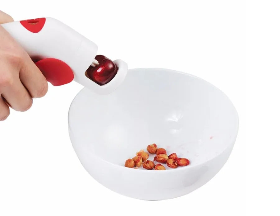 Close-up of a manual cherry pitter tool showing plastic handle and stainless steel mechanism.