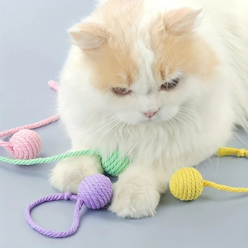 Green cat toy ball with attached rope on a wooden floor, shown next to a yellow 3cm size version.