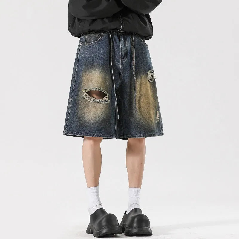 Man wearing loose fit retro blue ripped jeans with distressed details on a street style background.