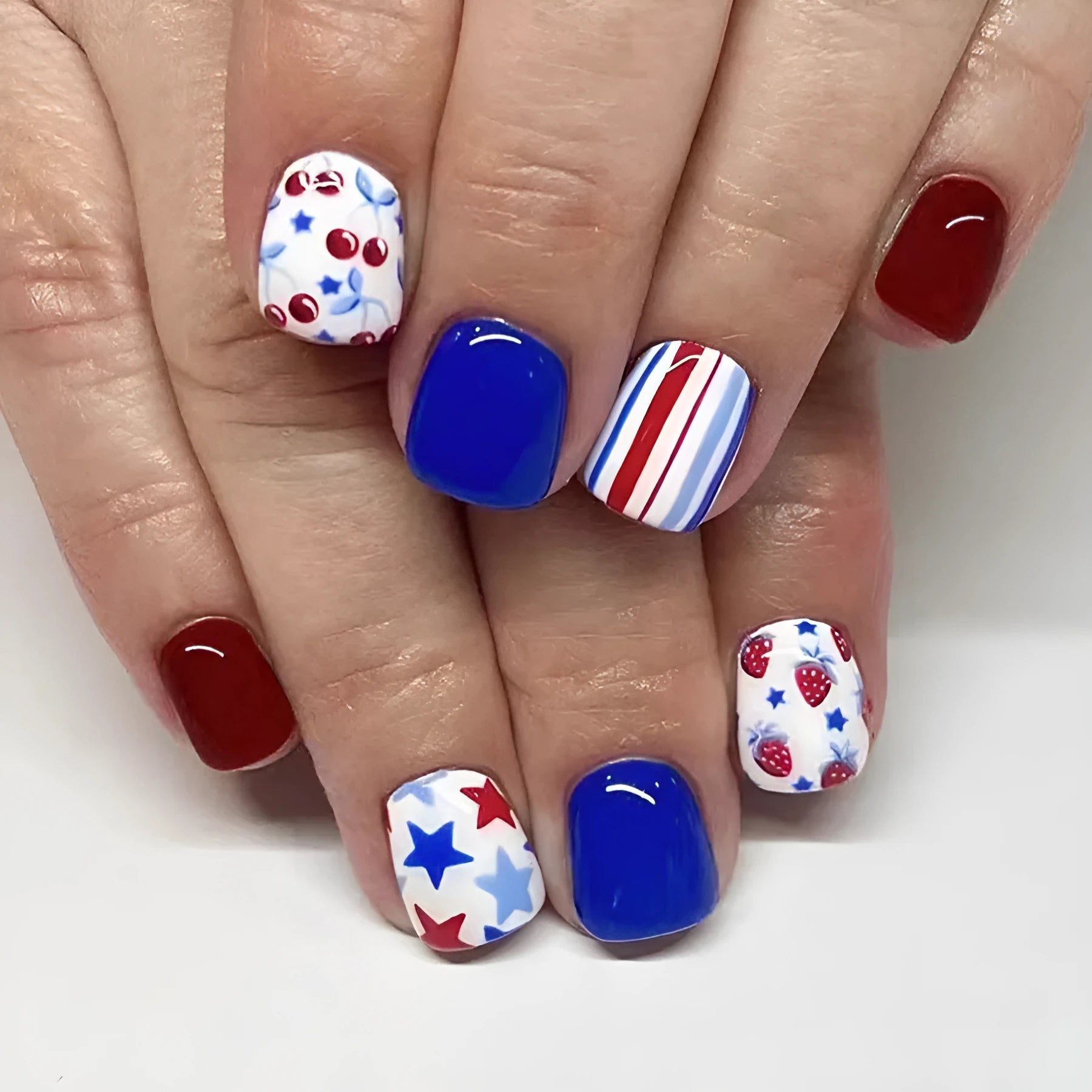 Set of 24 glossy red and blue press-on nail stickers with a strawberry pattern design for Independence Day.