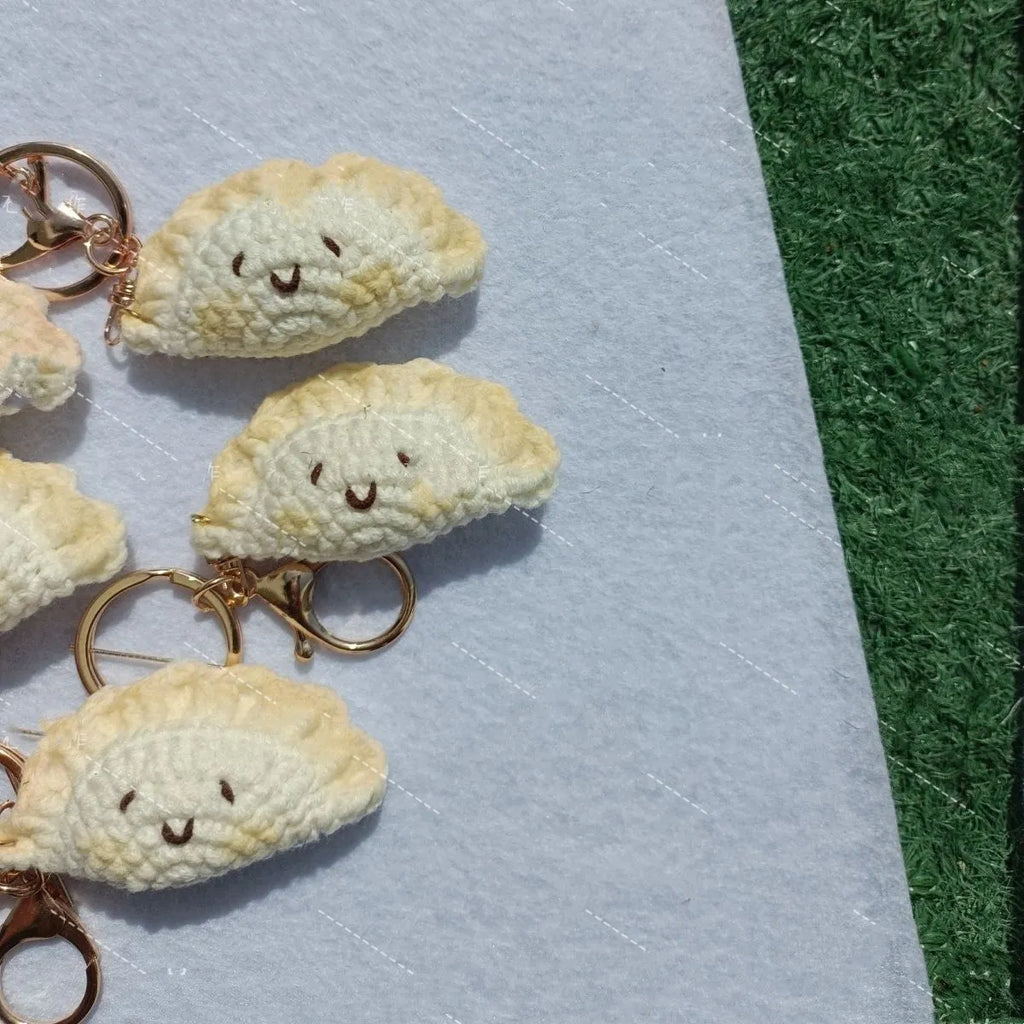 Handmade crochet dumpling pendant with Doudou Eye style and attached keychain on white background