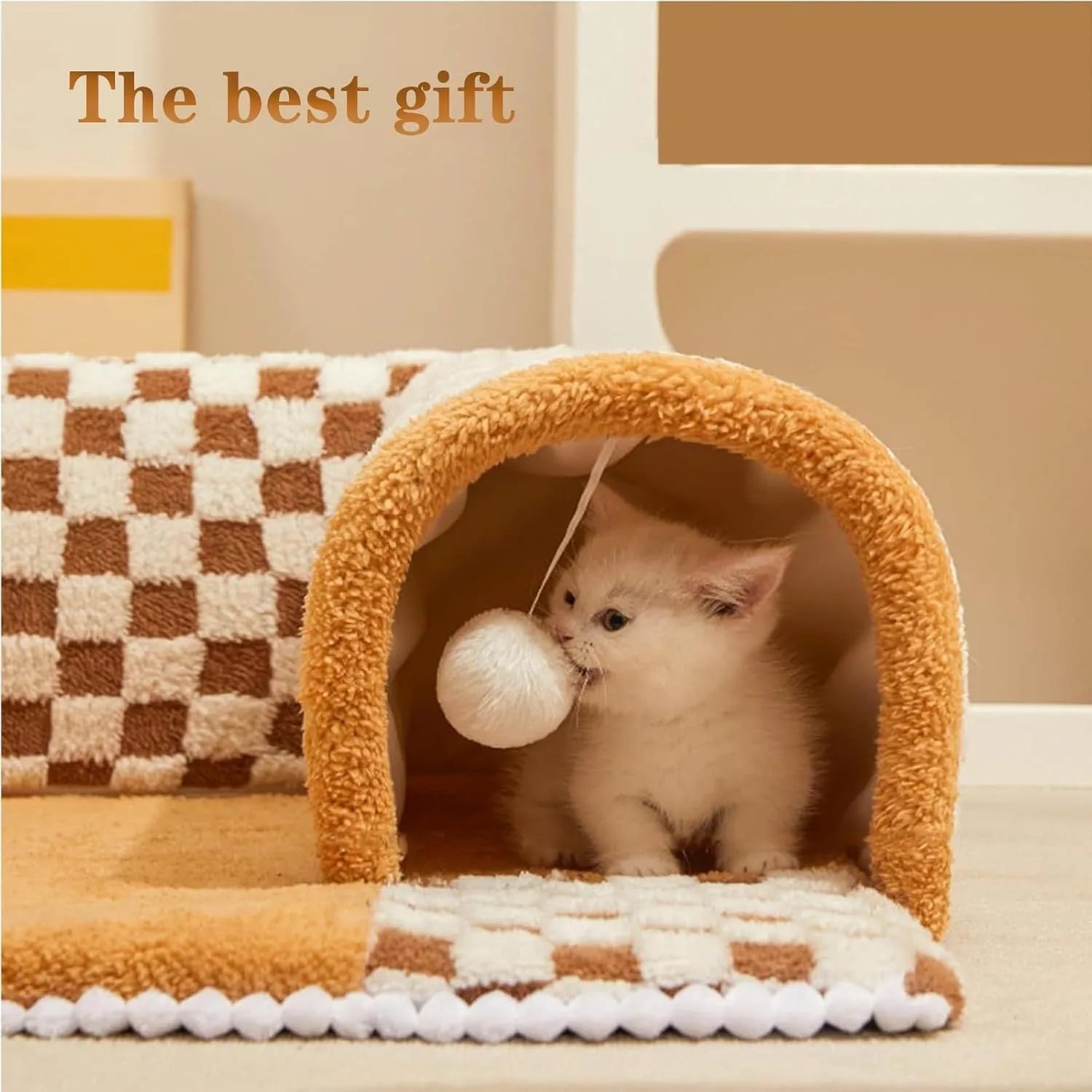 Brown plaid plush cat tunnel bed with a zippered side and central mat, shown on a wooden floor.
