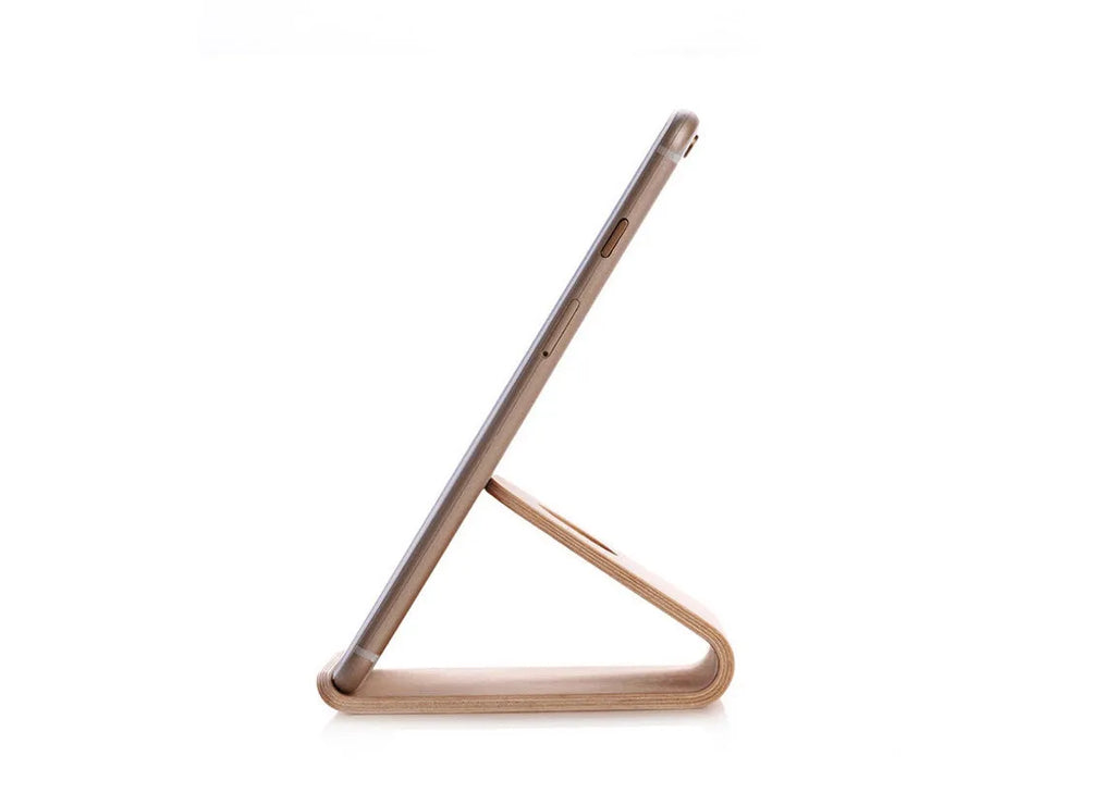 Solid walnut wooden iPhone stand holding a phone at an angle on a desk