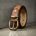 Men's brown leather belt with copper pin buckle on a pair of jeans.