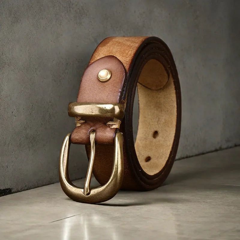 Men's brown leather belt with copper pin buckle on a pair of jeans.