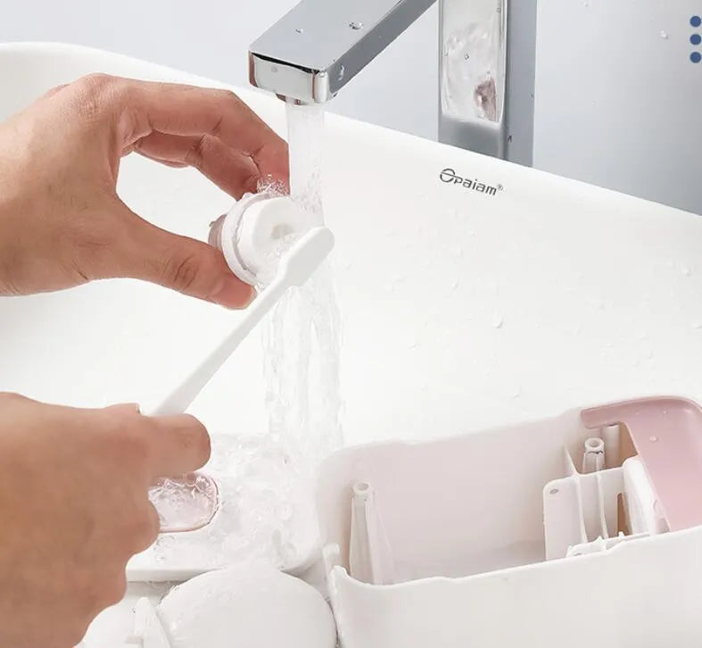 Automatic toothpaste dispenser unit mounted on a wall in a choice of blue, grey, or pink colours.