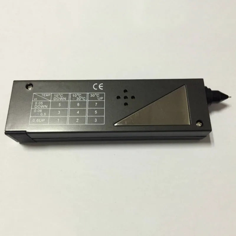 Black second generation diamond thermal conductivity tester with metal probe, shown with scale.