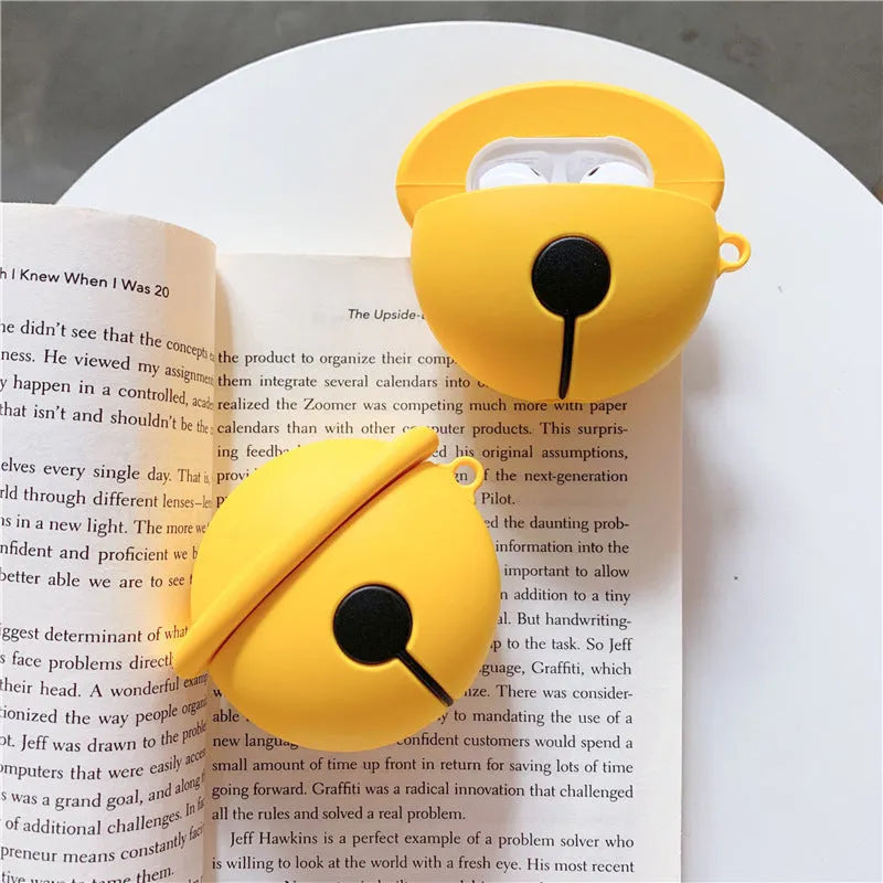 Yellow silicone protective case for AirPods with a small bell charm and a carry strap.