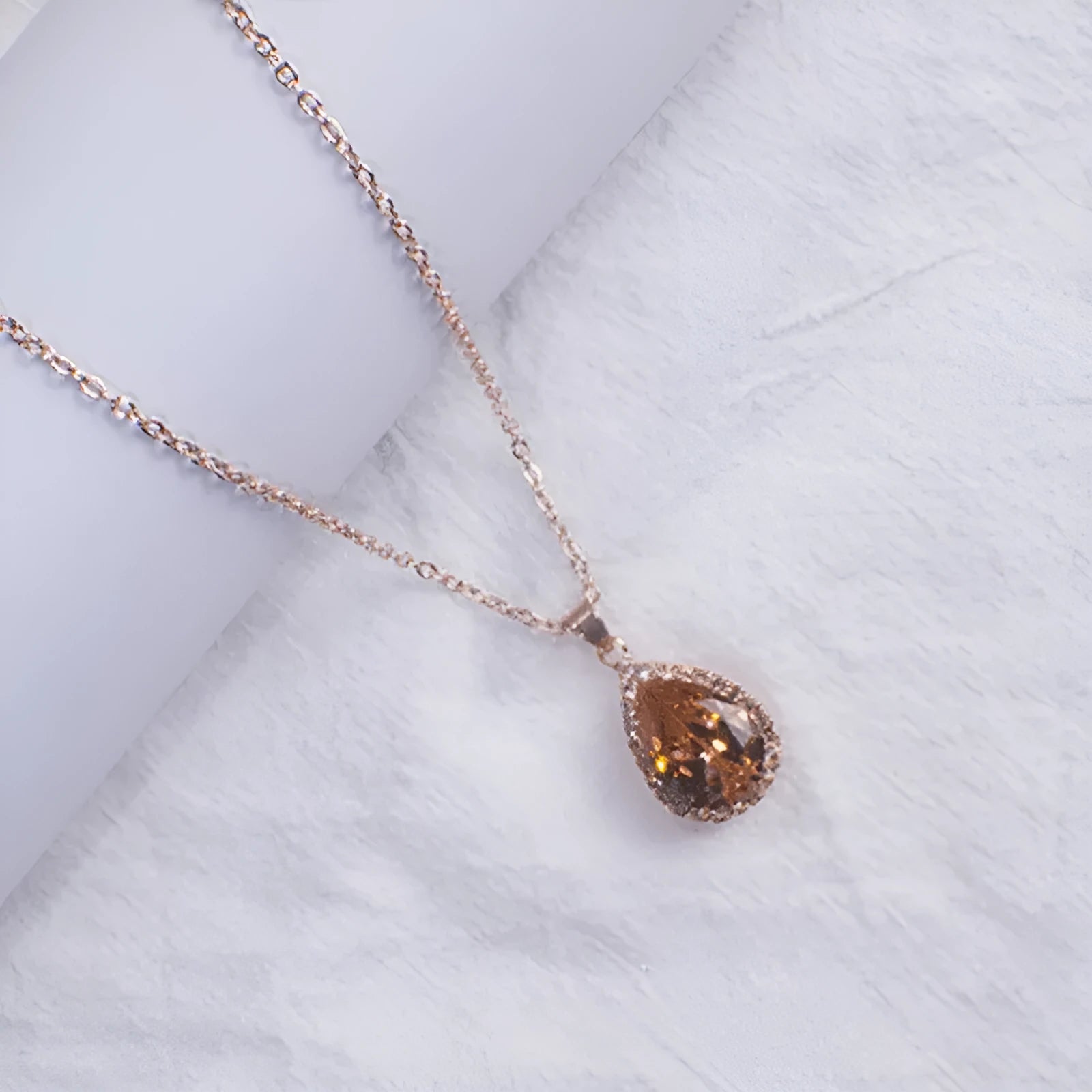 Rose gold electroplated necklace with water drop shaped geometric pendant and rhinestone detailing
