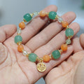 Jinsi Jade Duobao pumpkin bracelet with Prehnite bead on a flat surface, showing carved pumpkin bead and spacer beads