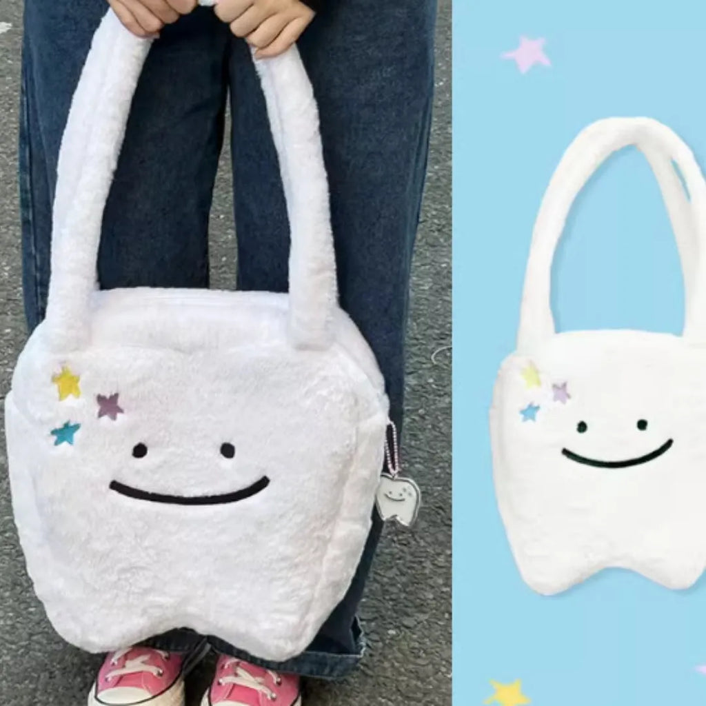 White plush tote bag with large cute teeth graphic, showing crossbody strap and zip opening.