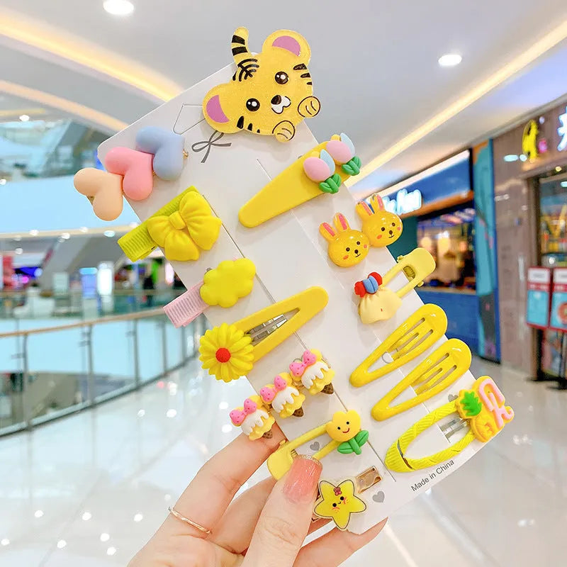 14-piece set of colourful toddler hair clips with candy, fruit, rainbow, and butterfly designs on a white background.