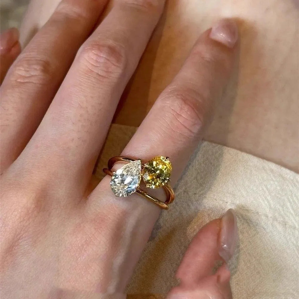 Geometric open copper ring for women with a water drop design set with contrasting zircon stones.