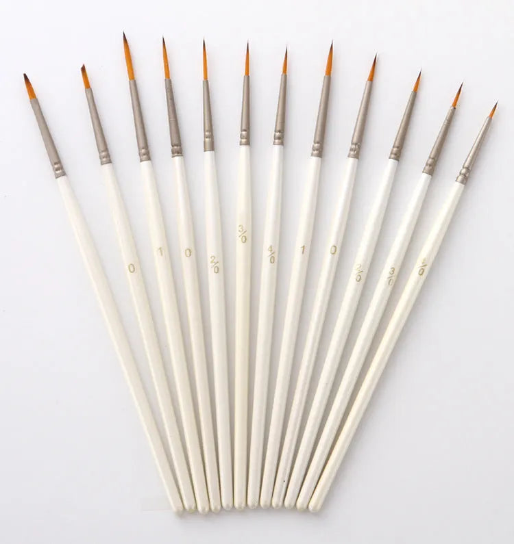 12 pearl white handled artist brushes with nylon wool bristles, stored upright in a solid wood pen holder.