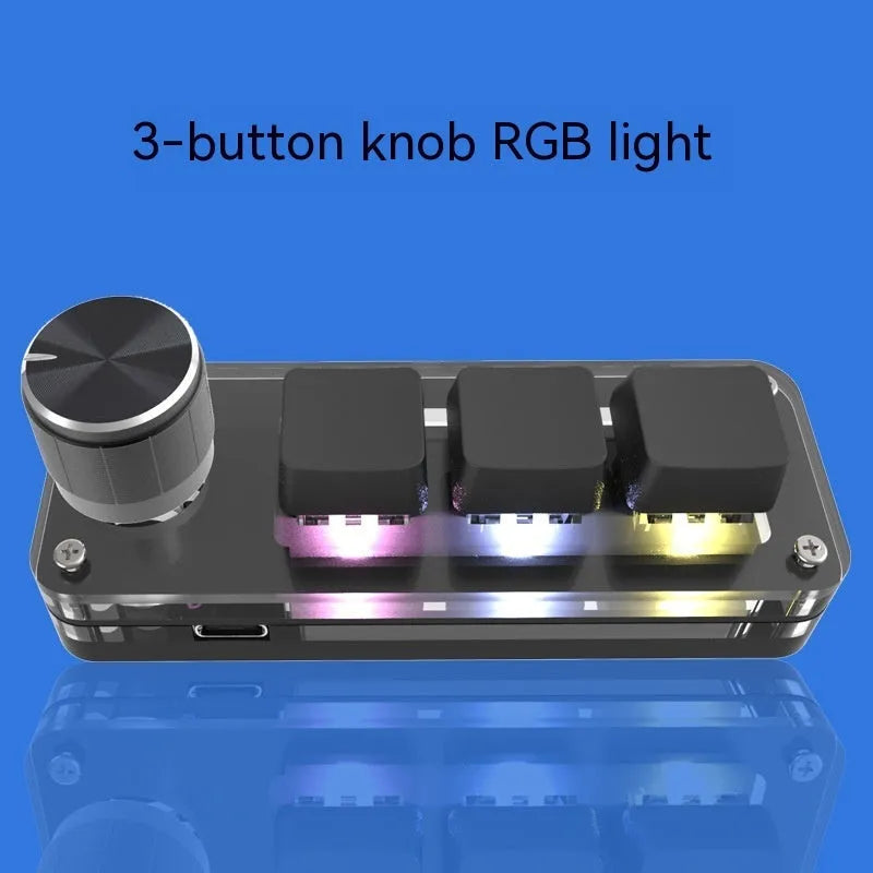 Black programmable mini keyboard with RGB backlighting on a desk next to a laptop
