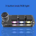 Black programmable mini keyboard with RGB backlighting on a desk next to a laptop