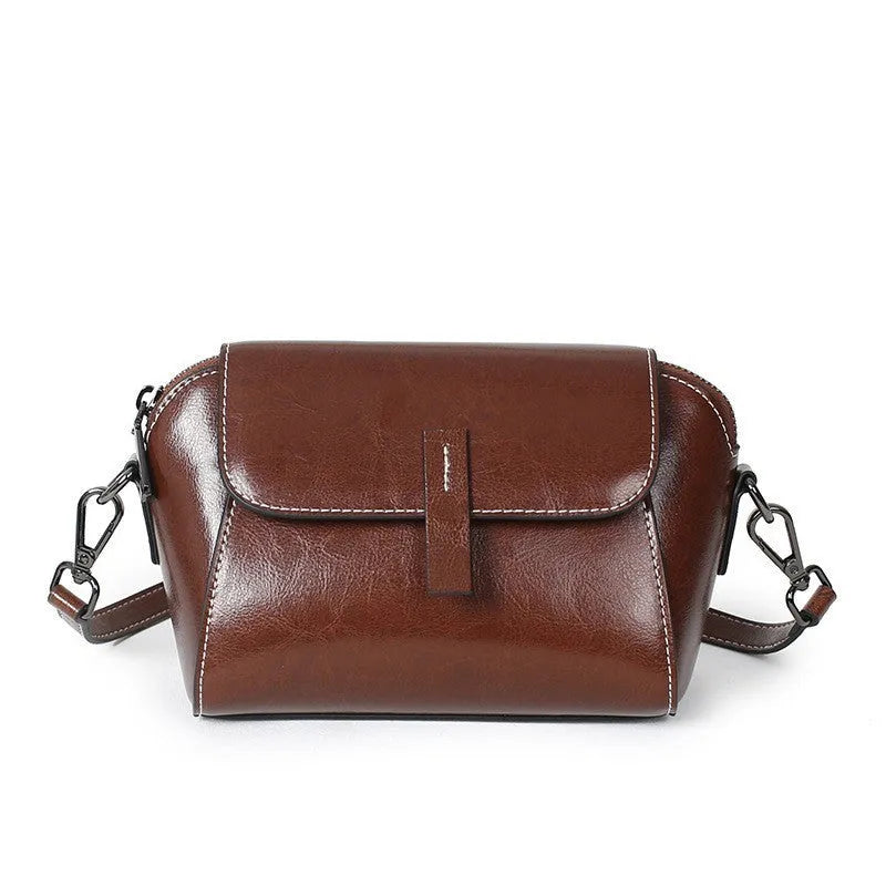 Brown women's shell-shaped genuine leather messenger bag with a single cross-body strap and visible stitching.