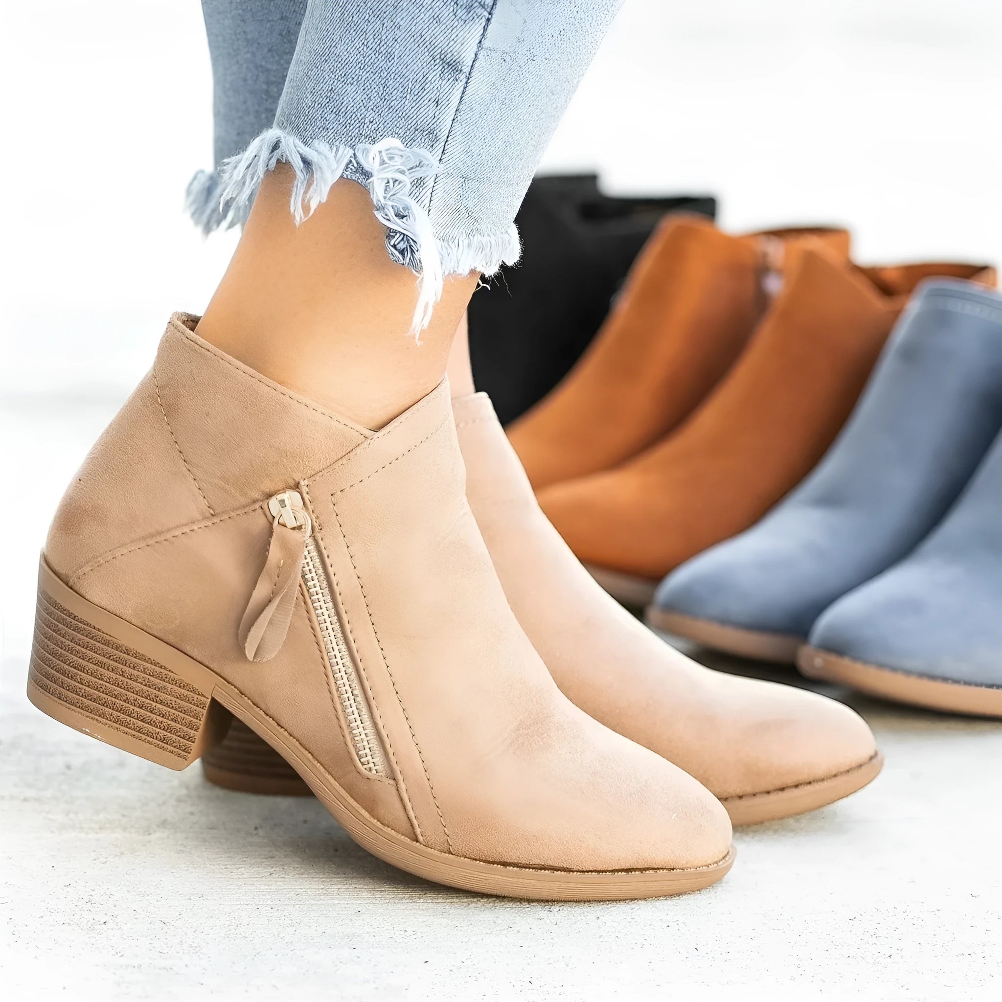 Women's beige suede ankle boots with a side zip and chunky block heel on a neutral background.