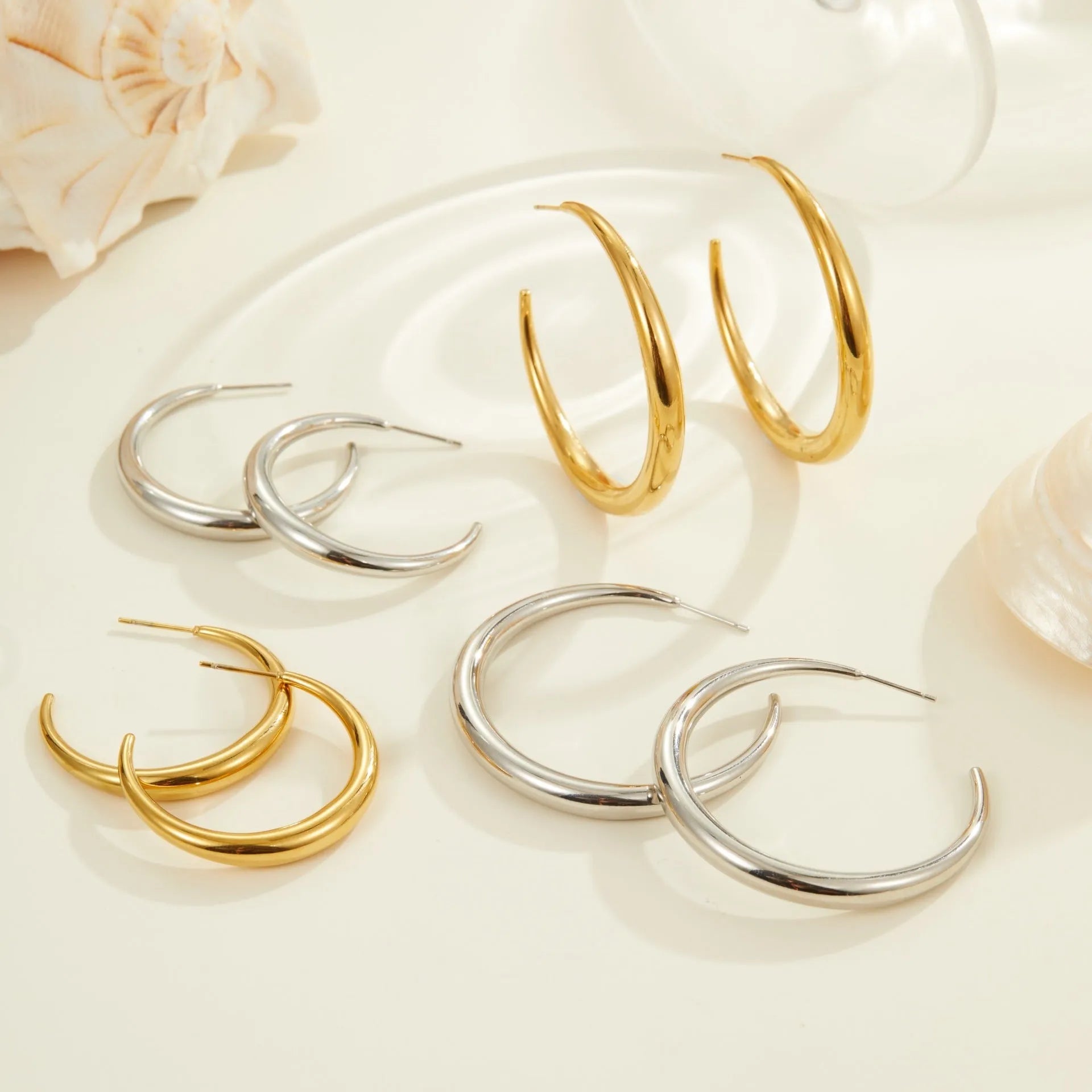 Simple round titanium steel hoop earrings for women in gold and steel finishes, shown in large and small sizes.