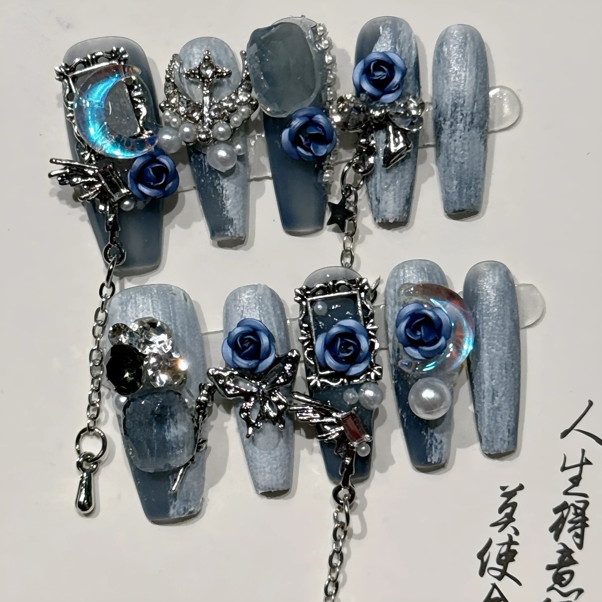 False nails with heavy industry blue colour and ornate rose and tulip flower patterns.