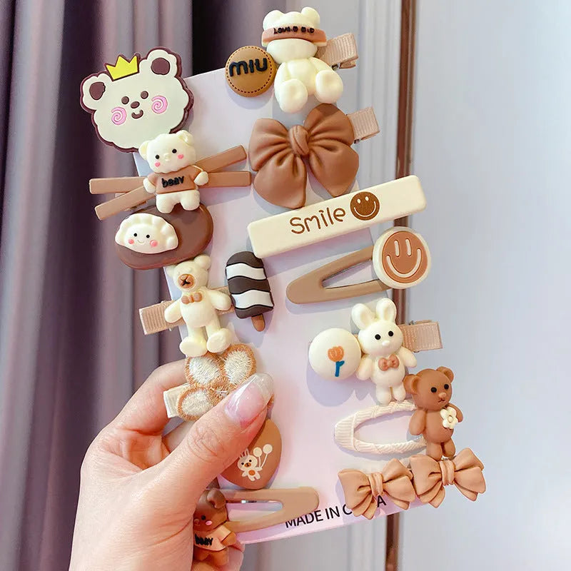 14-piece set of colourful toddler hair clips with candy, fruit, rainbow, and butterfly designs on a white background.