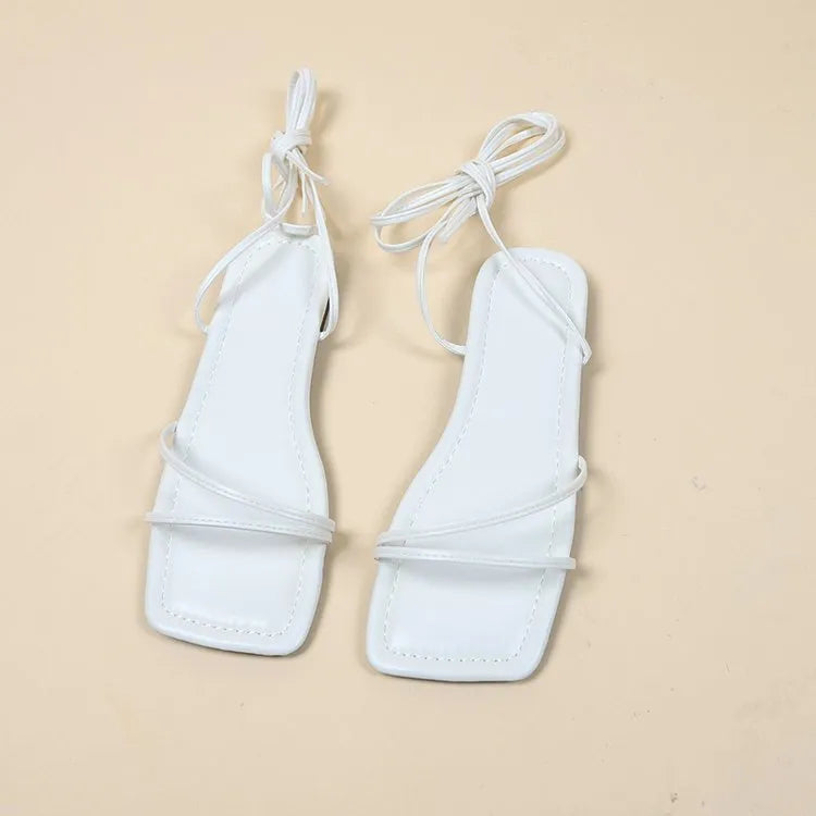 Women's white flat sandals with an ankle bandage cloth closure and square toe on a rubber sole.