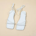 Women's white flat sandals with an ankle bandage cloth closure and square toe on a rubber sole.